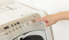 洗濯機のボタンを押す手