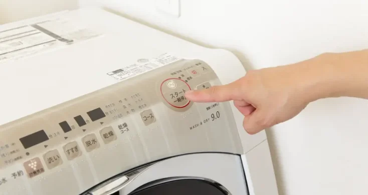 洗濯機のボタンを押す手